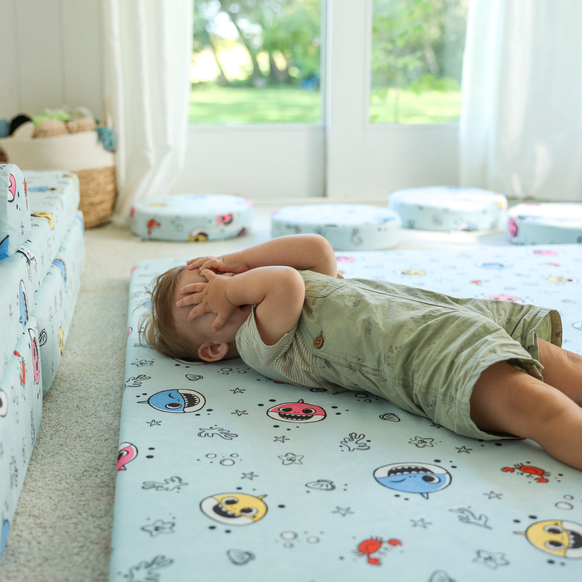 Toddler playing peek-a-boo on the Baby Shark™ x Roo & You™ Play Mat.