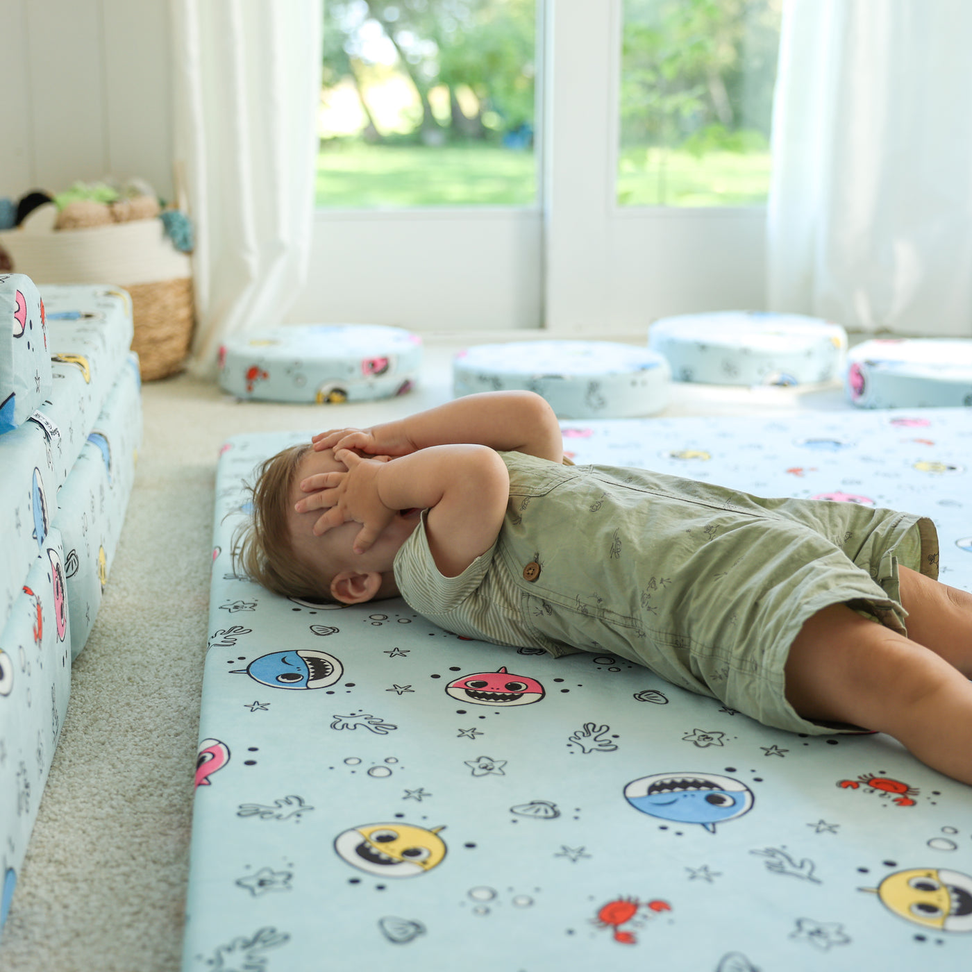 Toddler playing peek-a-boo on the Baby Shark™ x Roo & You™ Play Mat.