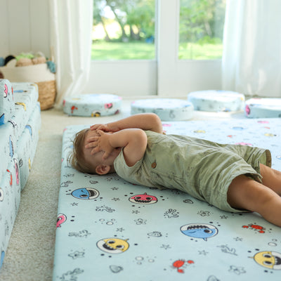 Toddler playing peek-a-boo on the Baby Shark™ x Roo & You™ Play Mat.