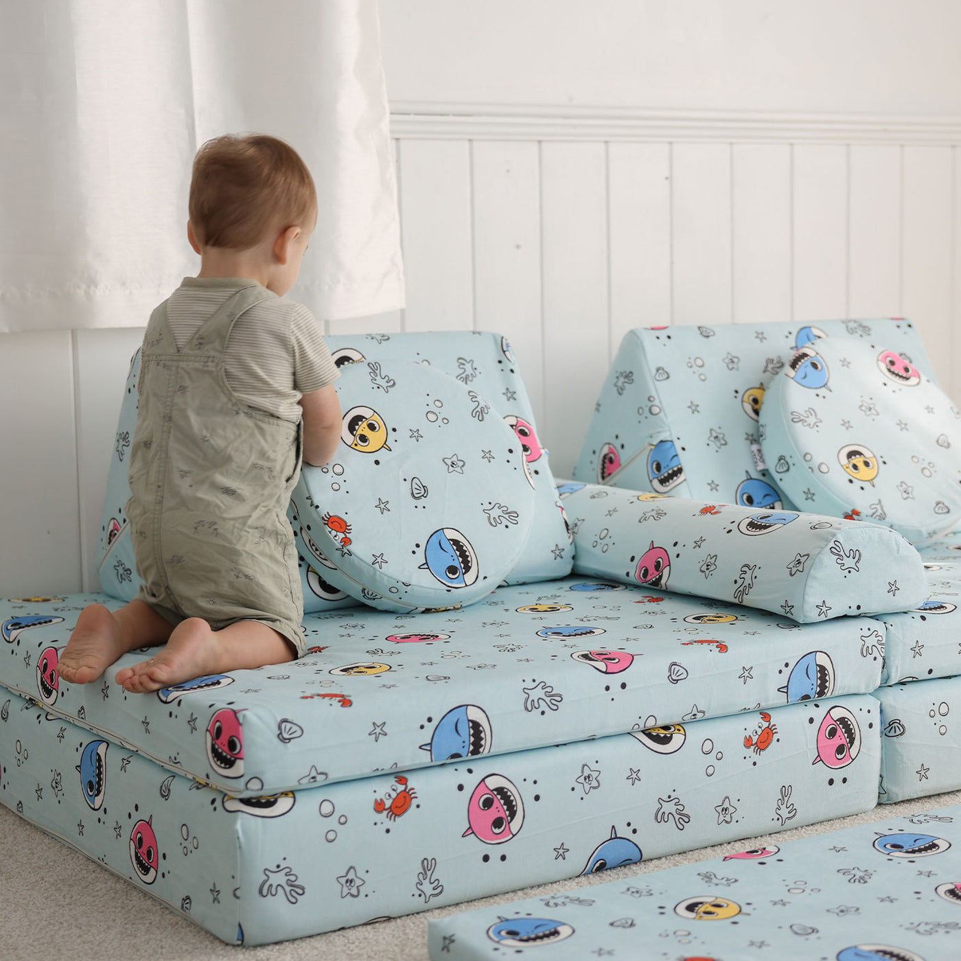 Toddler sitting on the Baby Shark™ x Roo & You™ Joey Play Couch with Baby Shark characters.